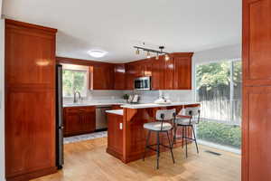 Kitchen featuring appliances with stainless steel finishes, light wood-type flooring, a breakfast bar area, light countertops, and a sink