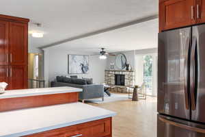 Kitchen featuring freestanding refrigerator, light wood-style floors, light countertops, a fireplace, and a ceiling fan