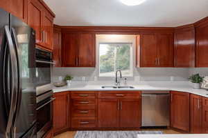 Kitchen featuring stainless steel appliances, a sink, light countertops, and light wood finished floors
