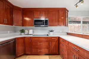 Kitchen featuring stainless steel appliances, light wood finished floors, light countertops, and brown cabinets