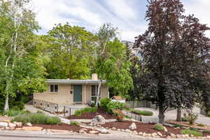 View of front of house featuring brick siding, a chimney, a fenced front yard, a porch, and driveway