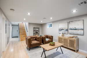 Living room with light wood-style floors, recessed lighting, stairs, and baseboards