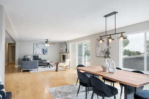 Dining room featuring a ceiling fan, light wood-type flooring, a fireplace, and baseboards