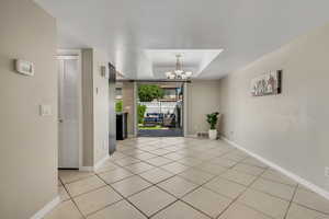 Foyer entrance with a raised ceiling, a chandelier, baseboards, and light tile patterned floors