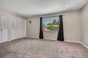 Unfurnished bedroom with carpet floors, two closets, and baseboards