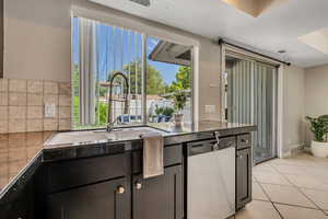 Kitchen featuring stainless steel dishwasher, a sink, and light tile patterned floors