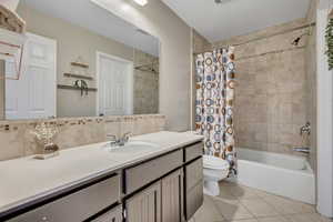 Full bathroom with vanity, shower / tub combo, tile patterned floors, toilet, and decorative backsplash