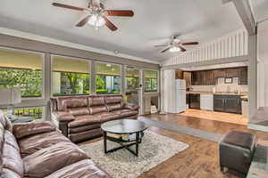Living room featuring a ceiling fan, lofted ceiling, and light wood-style floors