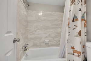 Bathroom featuring shower / tub combo with curtain and toilet