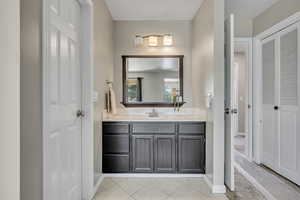 Bathroom with vanity, a closet, tile patterned flooring, and baseboards