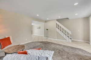 Carpeted living room with tile patterned flooring, stairs, recessed lighting, and baseboards
