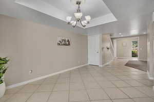 Spare room featuring light tile patterned floors, a chandelier, baseboards, stairs, and recessed lighting