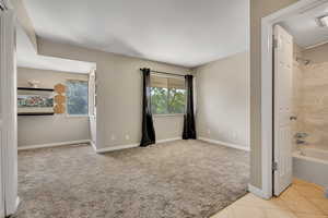 Unfurnished bedroom with carpet floors, baseboards, and ensuite bathroom