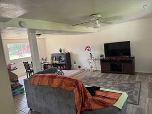 Living room with ceiling fan, wood finished floors, a textured ceiling, and baseboards