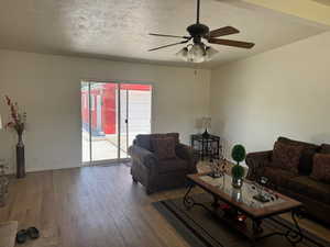 Living area featuring wood like vinyl finished floors, ceiling fan, a textured ceiling, and baseboards
