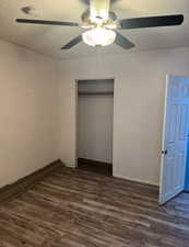 Unfurnished bedroom featuring dark wood-style floors, a closet, and a ceiling fan