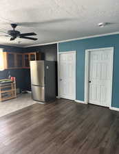 Unfurnished living room with a ceiling fan, dark wood finished floors, and a textured ceiling