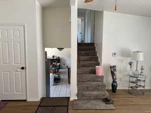 Stairs with wood finished floors, ceiling fan, and baseboards