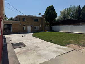 Rear view of house with a patio area and brick siding, photo taken from the corner of the yard.