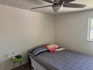 Carpeted bedroom with a ceiling fan and a textured ceiling