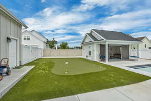 Fenced backyard with a putting area and a patio