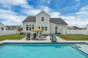 Back of property with an area to practice putting, a patio, board and batten siding, and a shingled roof