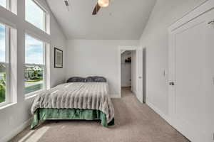 Bedroom featuring vaulted ceiling, multiple windows, light carpet, and ceiling fan