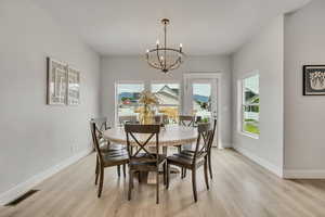 Dining space with light wood finished floors, a chandelier, and baseboards