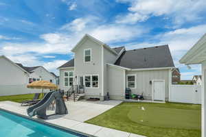 Back of house featuring a putting green, a patio area, board and batten siding, a fenced backyard, and a shingled roof