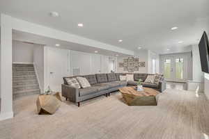 Living room featuring baseboards, recessed lighting, stairway, and light carpet