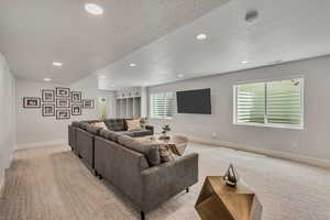 Living area featuring recessed lighting, baseboards, and light colored carpet