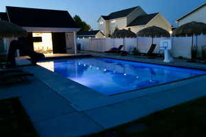 View of pool with a fenced backyard, a water slide, and a patio area