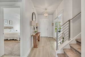 Foyer entrance with stairs, baseboards, light wood-type flooring, and a chandelier