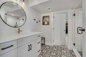 Bathroom featuring a shower stall, vanity, and baseboards