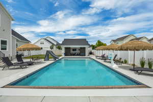 View of swimming pool featuring a water slide, a fenced backyard, a storage structure, and a patio area