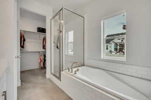 Full bath with a shower stall, a bath, tile patterned floors, a spacious closet, and healthy amount of natural light