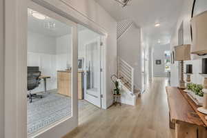 Corridor featuring light wood-type flooring and a chandelier