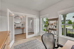 Office area with healthy amount of natural light, light wood-type flooring, a chandelier, and french doors