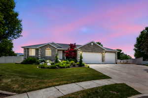 Ranch-style house featuring driveway, stone siding, and an attached garage