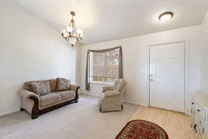 Living room featuring a chandelier, baseboards, and vaulted ceiling