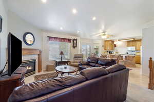 Living area with a fireplace, a ceiling fan, recessed lighting, and lofted ceiling