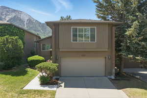 View of front of home featuring an attached garage, concrete driveway, a mountain view, and a front lawn