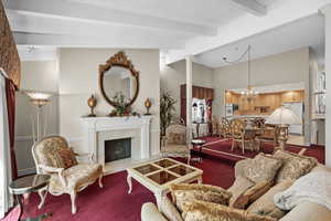 Living area with carpet floors, a high end fireplace, and a chandelier