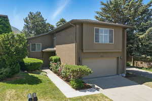 View of side of property with a garage, concrete driveway, brick siding, and a yard