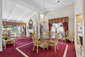 Carpeted dining space featuring a textured ceiling, a chandelier, a fireplace, and baseboards