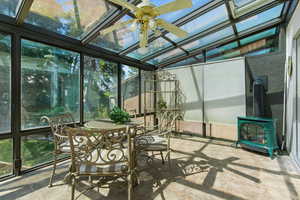 Sunroom / solarium featuring a ceiling fan and a wood stove