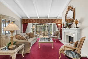 Carpeted living area with a textured ceiling, beamed ceiling, a premium fireplace, and plenty of natural light