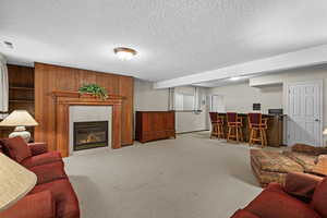 Carpeted living room with a dry bar, a textured ceiling, and a fireplace