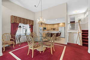 Dining room featuring a chandelier, light carpet, a towering ceiling, and stairs