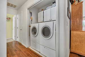 Laundry room with separate washer and dryer, cabinet space, dark wood-type flooring, and baseboards